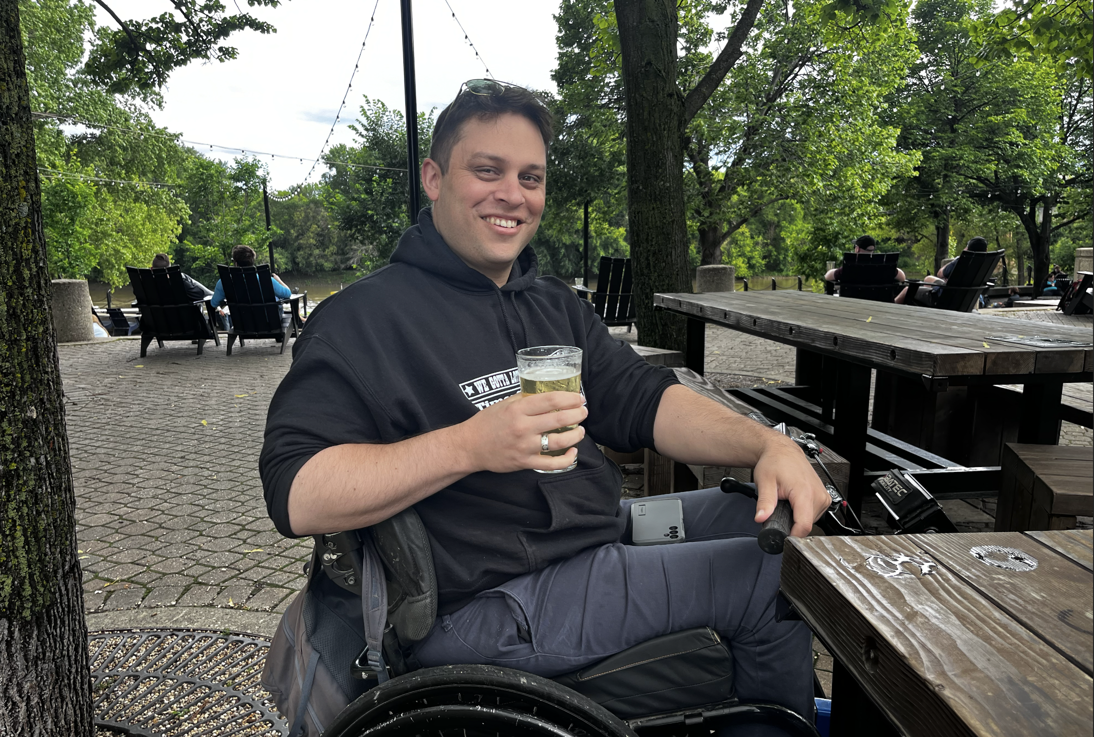 Cheers! Peters lifts his pint to you. His other arm rests on the e-bike attachment for his wheelchair. Behind him is the hustle and bustle of an evening at the Forks.