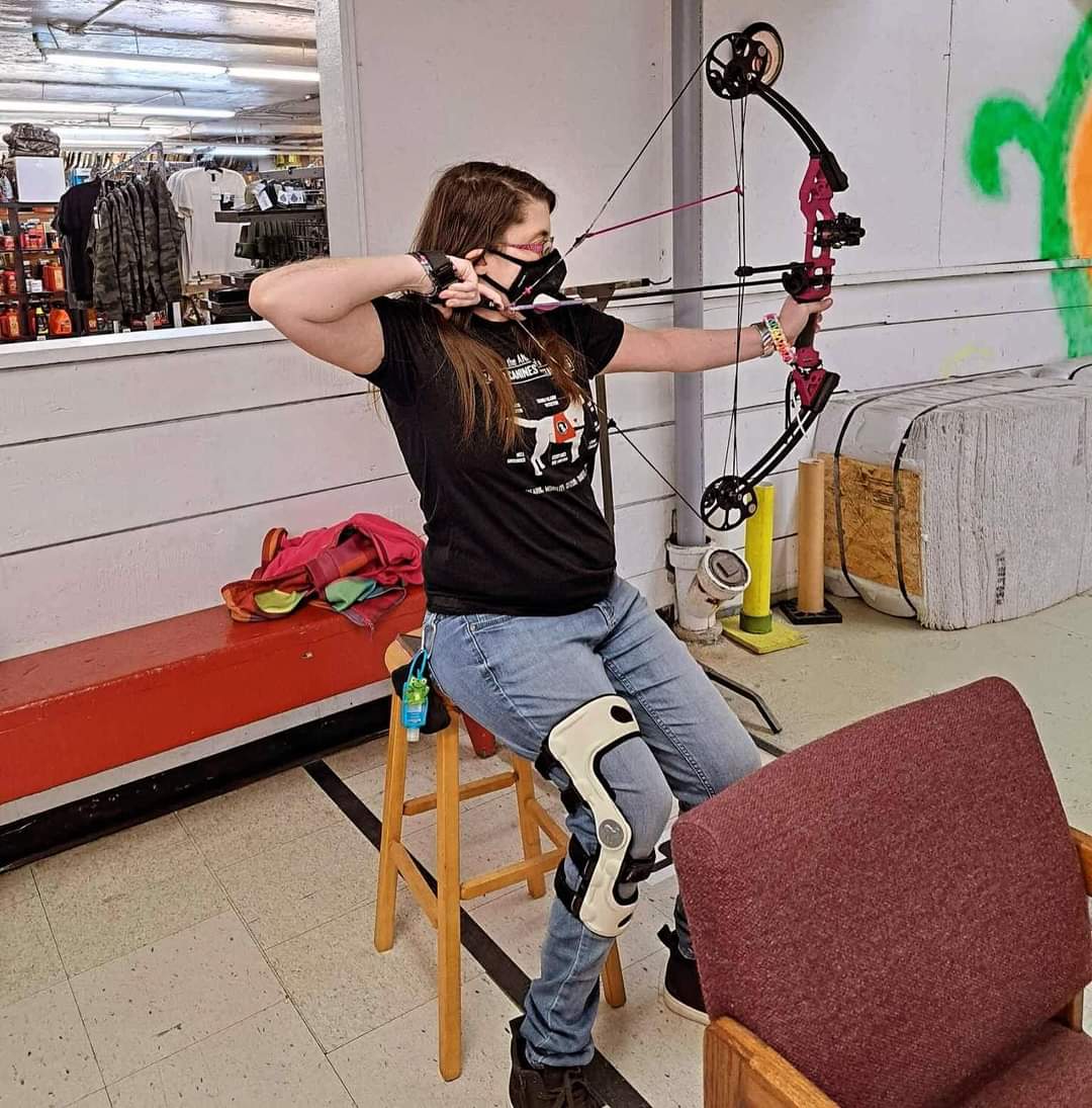 Our friend Kerri, seated on a stool about to release her arrow at Blind Sports Archery.